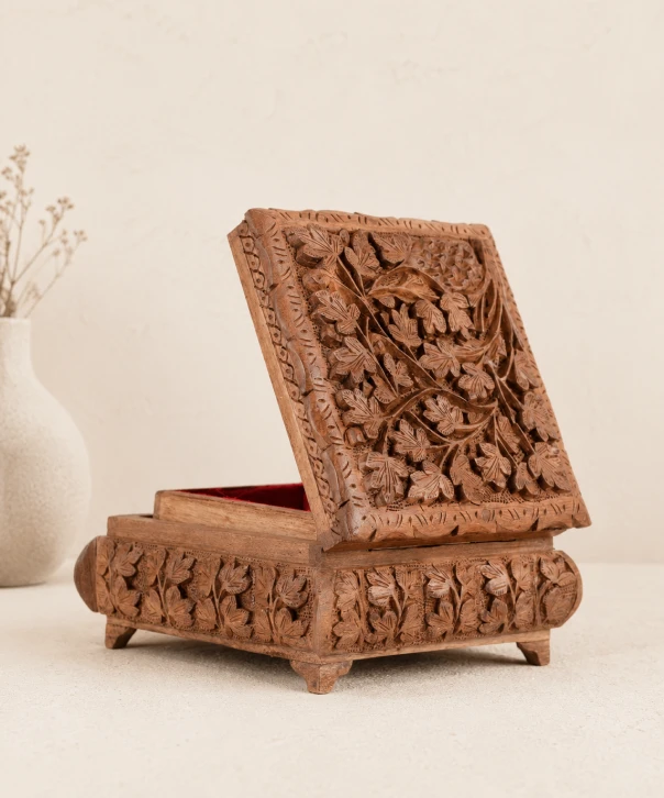 Hand-carved Kashmiri walnut wood keepsake box with an open lid, showcasing intricate floral carvings and traditional artisan craftsmanship.