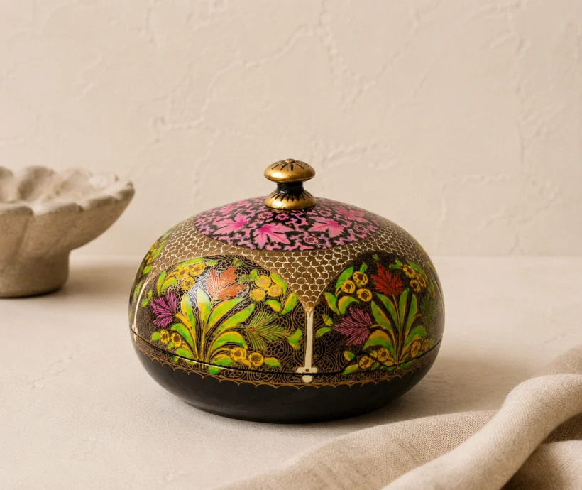 Handcrafted Kashmiri papier-mâché trinket box with a domed lid, featuring vibrant floral artwork and intricate hand-painted detailing on a black background.