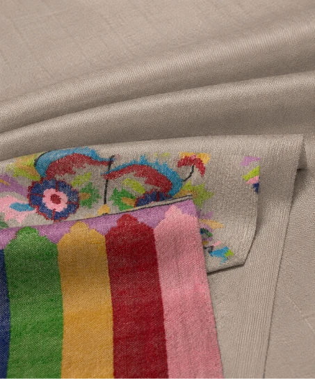 Close-up of the handcrafted Kashmiri shawl highlighting colorful floral woven motifs, decorative striped border detailing, and the soft woven fabric texture.