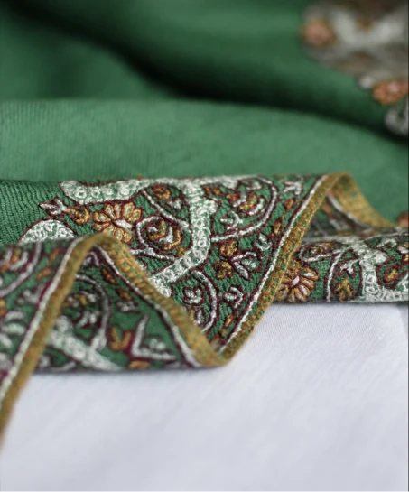 Close-up of the handcrafted Kashmiri shawl highlighting intricate floral embroidery, decorative border detailing, and the soft woven texture.