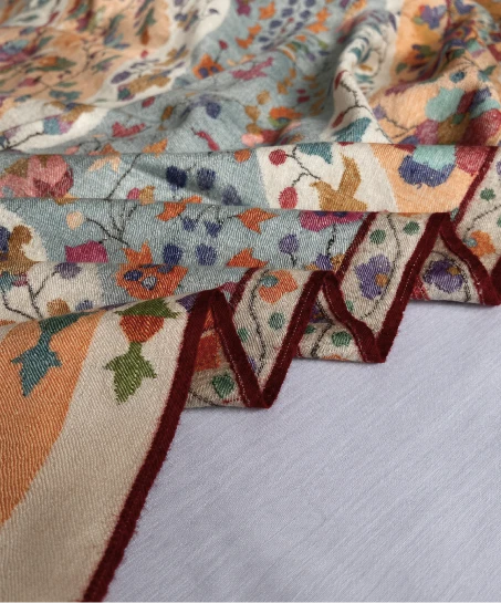 Close-up of the handcrafted Kashmiri shawl highlighting intricate woven floral motifs, decorative border detailing, and the soft, luxurious fabric texture.