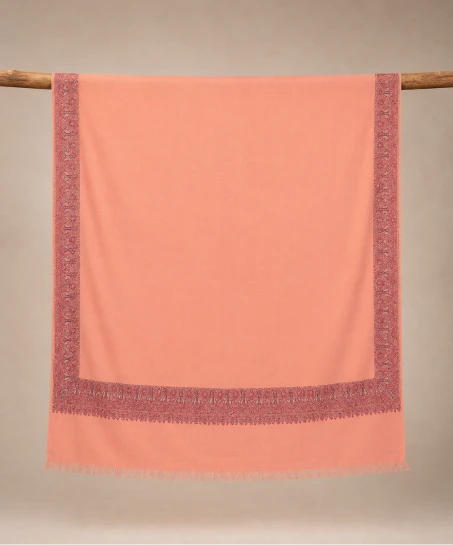 Handcrafted Kashmiri embroidered shawl displayed flat, featuring a solid peach body with detailed paisley and floral embroidered borders and delicate fringed edges.