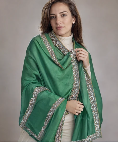 Model wearing a handcrafted Kashmiri embroidered shawl in emerald green with intricate floral embroidered borders and soft woven fabric.